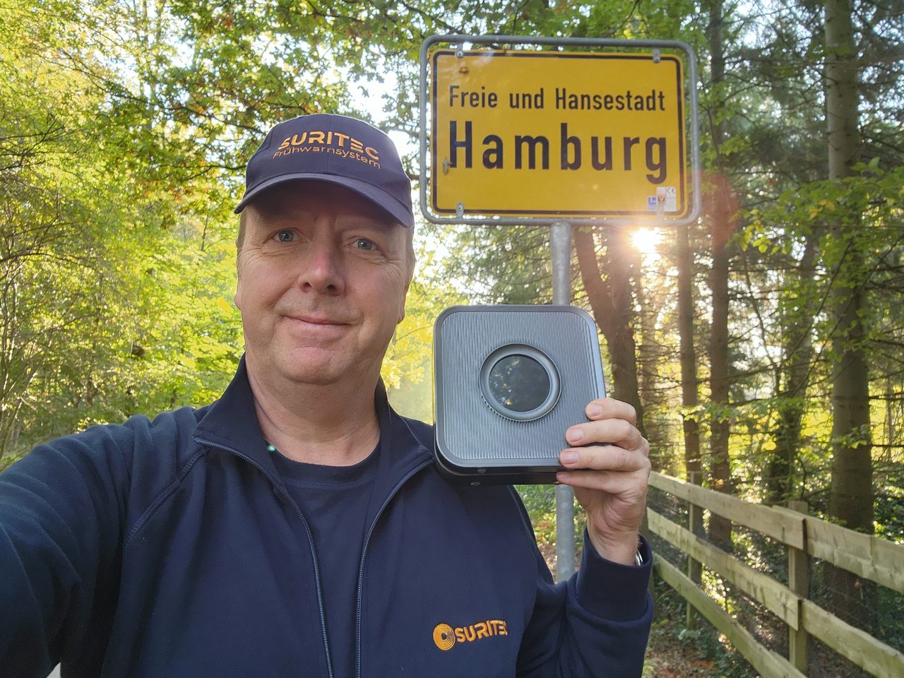 Michael Meyer mit dem Frühwarnsystem FRED am Ortsschild Hamburg